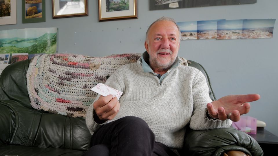 Austin Allen laughing on a sofa, holding a card
